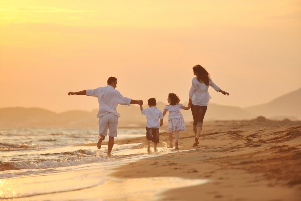 happy young family have fun on beach run and jump  at sunset